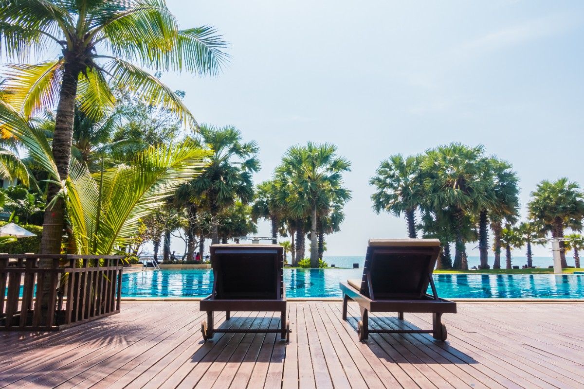 Modern Dubai pool area featuring professional landscape design with stone paving, palm trees, ambient lighting, and outdoor lounge space